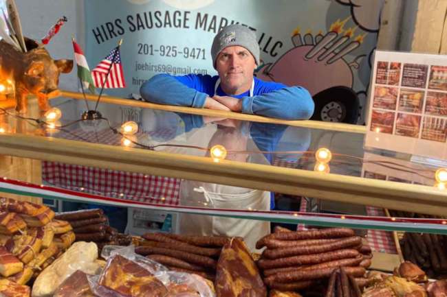 Jozsef Hirs, owner of Hirs Sausage Market, standing behind a meat case