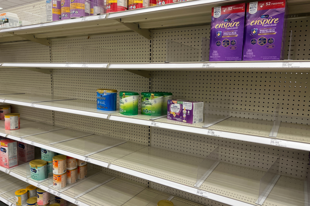 Photo of mostly empty grocery store shelves in the baby formula section