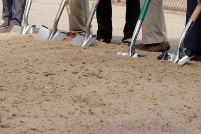 Executives with shovels in soil at ground breaking event