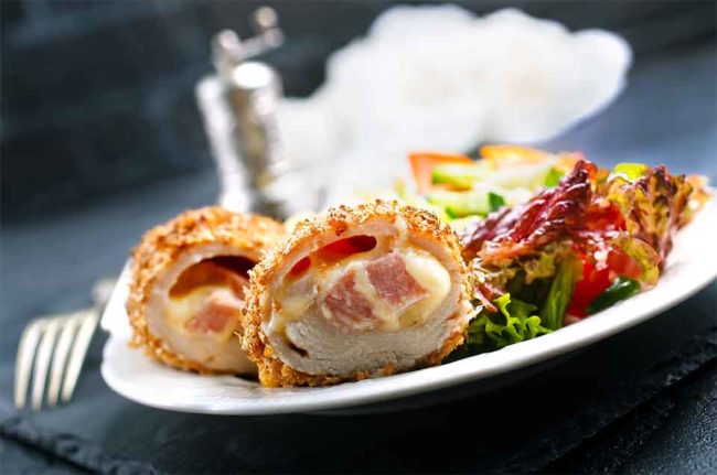 A plate of chicken cordon bleu with leafy green salad