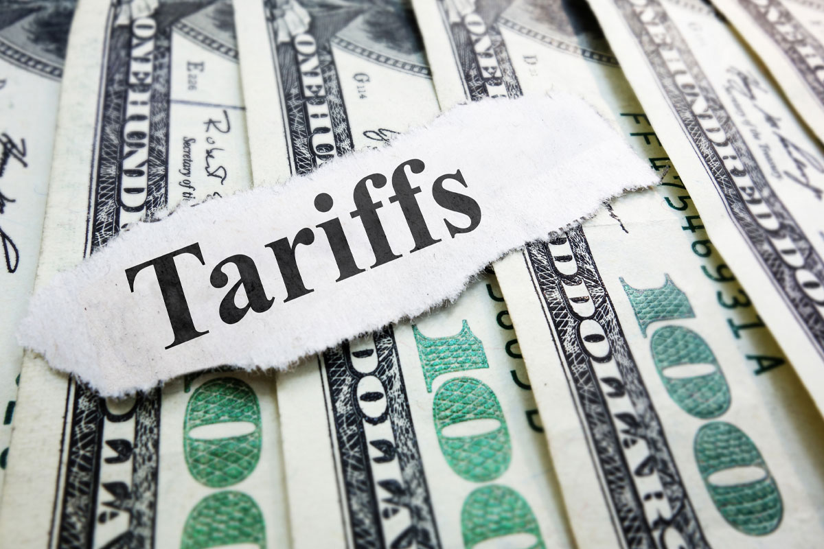 Tariffs newspaper headline on top of $100 bills