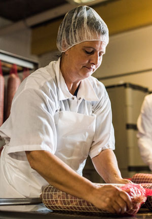 An employee at Volpi Foods nets fresh coppa before hanging it to cure.
