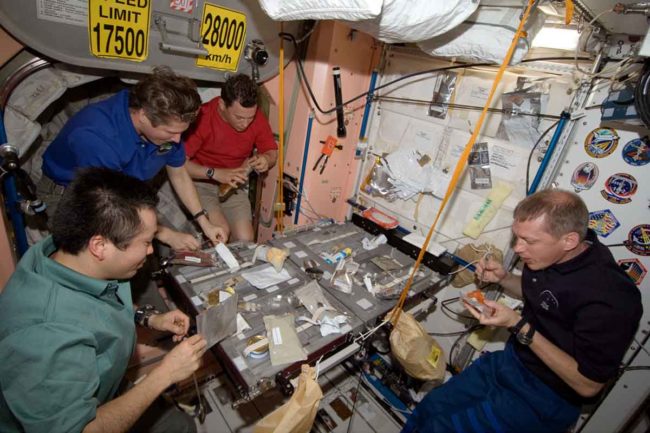 Crew members share a meal in the Unity Module of the International Space Station.